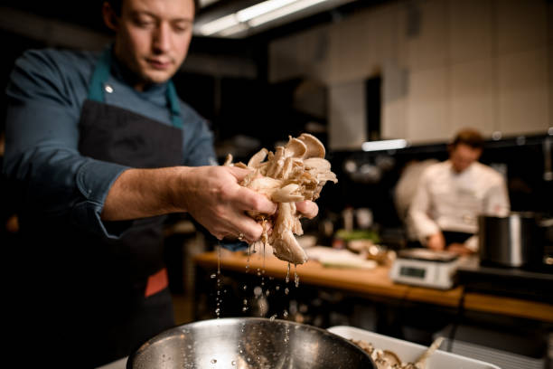 istock male chef holds oyster mushrooms over bowl on kitchen 1302140237