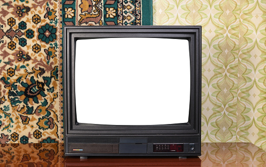 Old black vintage TV with white screen to add new images to the screen TV set against wallpaper and carpet from 1980-1990.