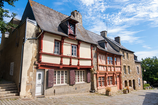 Street with historic buildings and a stream on the outskirts of Falaise. Saint-Laurent church on a hill in the background