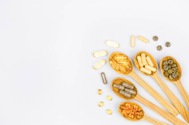 variety of dietary supplement pills in wooden spoons - fish oil vitamin e cod liver oil nutritional supplement imagens e fotografias de stock