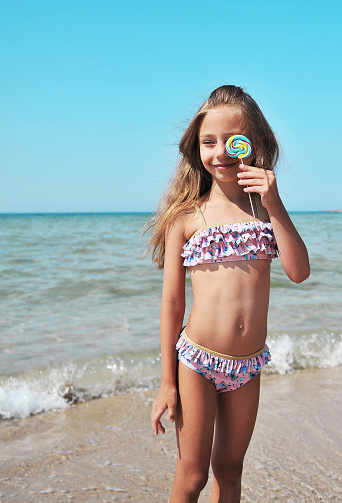 Cute little girl with ice cream has fun on the beach. Summertime concept.