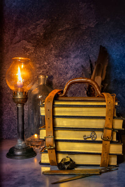 istock Stack of Books Bound By Leather Strap lit by Candle Light 1302145734
