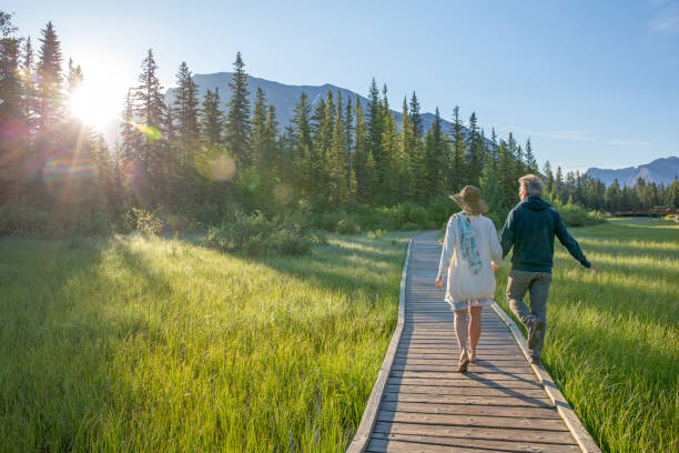 Couple walk down boardwalk over marsh, sunrise