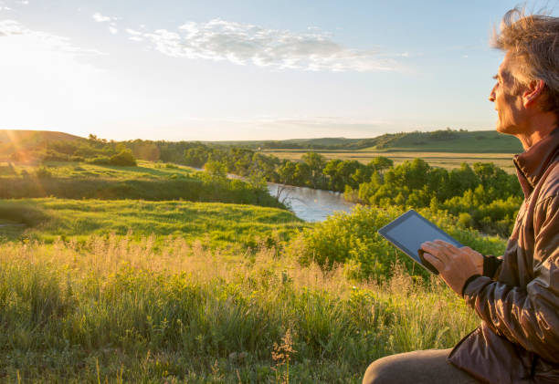 istock Man uses digital tablet at sunrise on prairies 1302146930