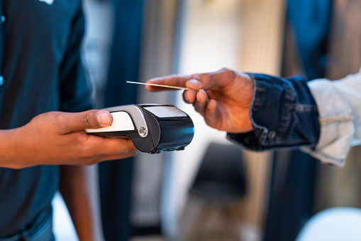 A store clerk extends his hand for the customer to pay by means of a dataphone when contacting his purchase