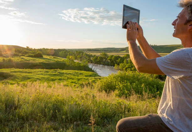 Man uses digital tablet at sunrise on prairies