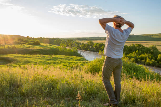 man stretches on prairie meadow and river, sunrise - achievement mature adult adult mountain range imagens e fotografias de stock