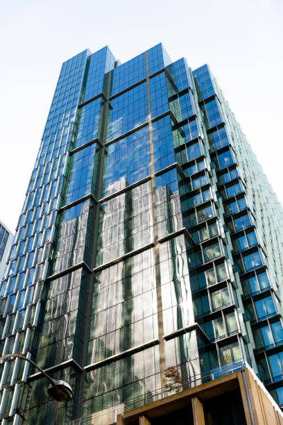 istock Low angle view of modern office building with reflection, skyscrapers, sky background with copy space 1302147098