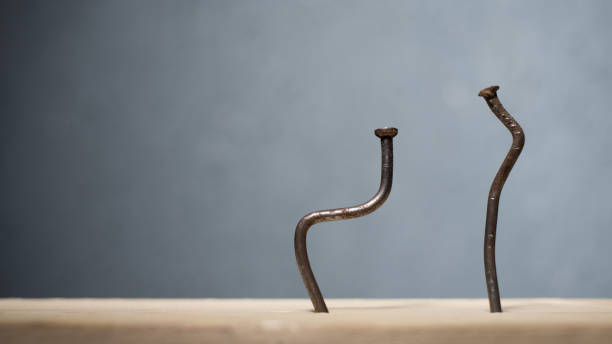 dos clavos doblados en una tabla. concepto stoop, ciática y enfermedad degenerativa del disco - encorvado fotografías e imágenes de stock