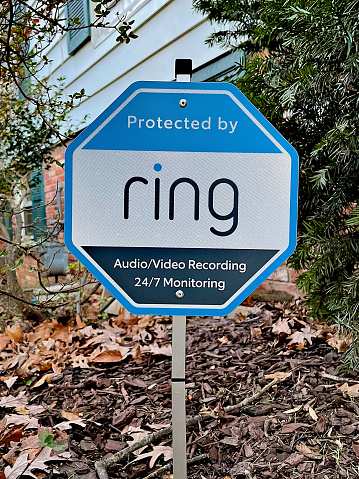 Fairfax, Virginia / USA - January 21, 2021: A yard sign warns would-be burglars that a suburban home is protected by Ring audio and video surveillance and security monitoring.