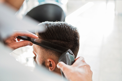 Modern men's haircut ,hairdresser using electric razor