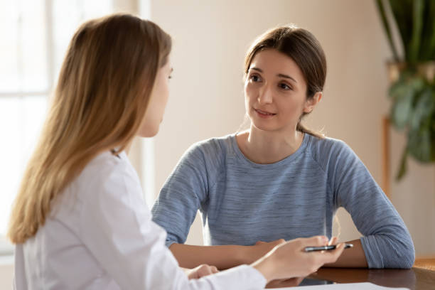 Millennial female visitor of clinic discussing problem with trusted physician I trust my GP. Millennial female or teenage girl student patient visitor of clinic discussing problem diagnosis with trusted physician, listening to explanations and advices of good capable specialist recruiter photos stock pictures, royalty-free photos & images