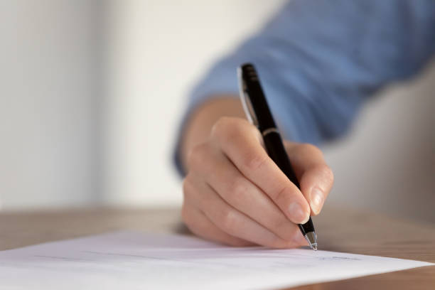 istock Young female hand with pen ready to sign paper document 1302150571