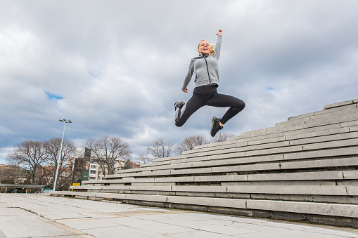 Healthy mid adult woman running in the city and jumping.
