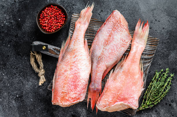 istock Raw Red perch or seabass fish on a cutting board. Black background. Top view 1302152128