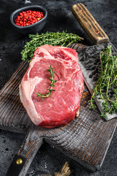 istock Raw beef striploin on the bone meat steak. Black ground. Top view 1302152231