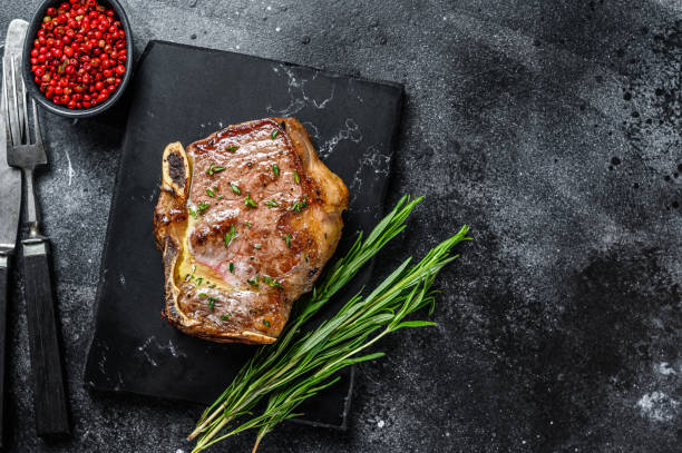 istock Grilled striploin steak on the bone or new york steak. Black background. Top view. Copy space 1302152991