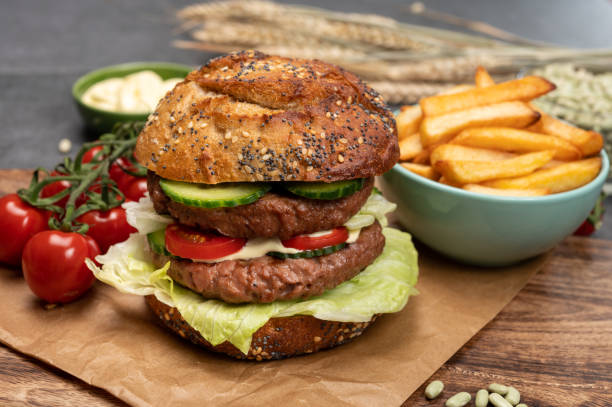 istock Tasty vegetarian vegan lunch with double decker hamburger made from plant based soya beans burger, organic bun with seeds and fresh vegetables and french fried potatoes 1302153104