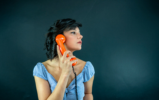 Cheerful vintage style woman on the phone, she is holding the receiver and smiling