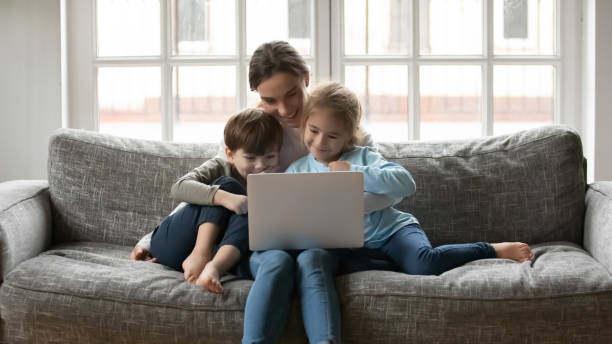 istock Smiling affectionate young mother watching cartoons on computer with kids. 1302153184