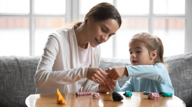 istock Caring young mother making plasticine figures with little daughter. 1302153201