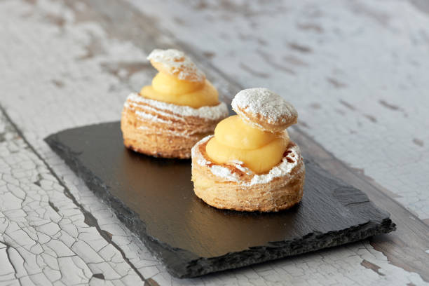 istock Appetizing puff pastry cakes filled with pastry cream on a black plate. 1302153211