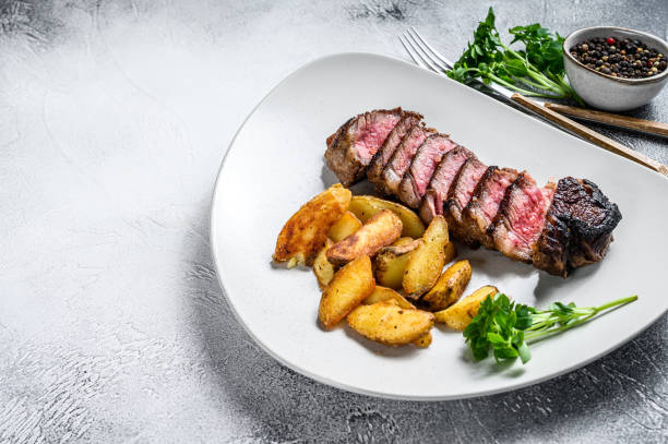 istock Sliced Grilled rump Beef steak with potato. White background. Top view. Copy space 1302154670