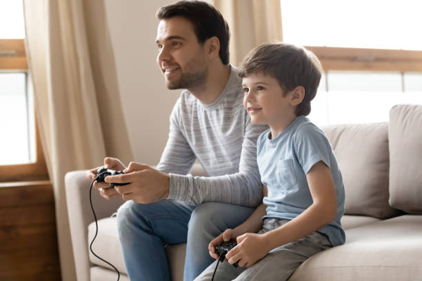 istock Excited dad and small son play video game 1302155996