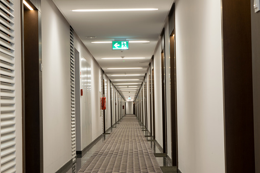 View of the long corridor in the hotel, lots of doors on both sides.