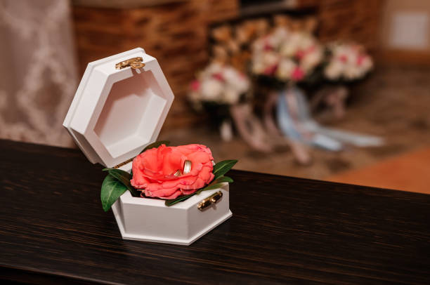 istock Wedding gold rings on an orange rose in a white box 1302157324