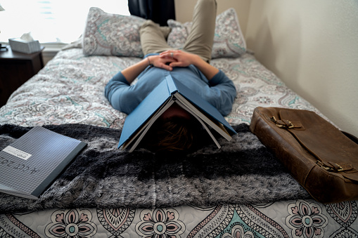 A Young College Student Studying For An Exam, Couldn't Take It Any More And Decided To Get Some Well Deserved Shut-eye, With A Book Covering His Face