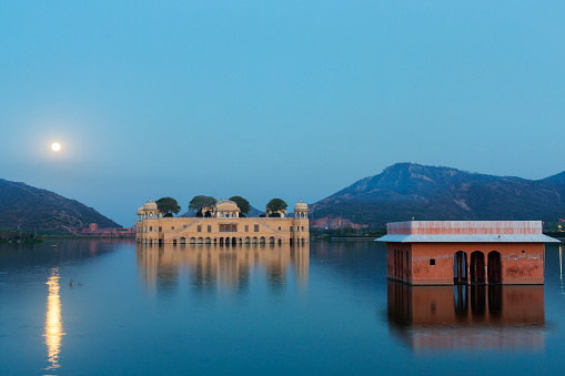 The Jal Mahal water palace in the middle of Man Sagar Lake in Jaipur, Rajasthan, India at night with a full moon