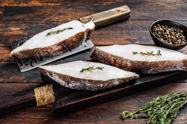 istock Raw halibut fish steak. Dark wooden background. Top view 1302159489
