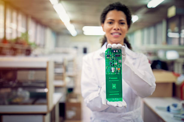 retrato de una mujer sosteniendo una placa de circuito en una fábrica - african descent factory accuracy analyzing fotografías e imágenes de stock