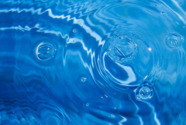 istock Blue swimming pool water background with drops and bubbles. Ripple shapes with sun reflections. 1302160591