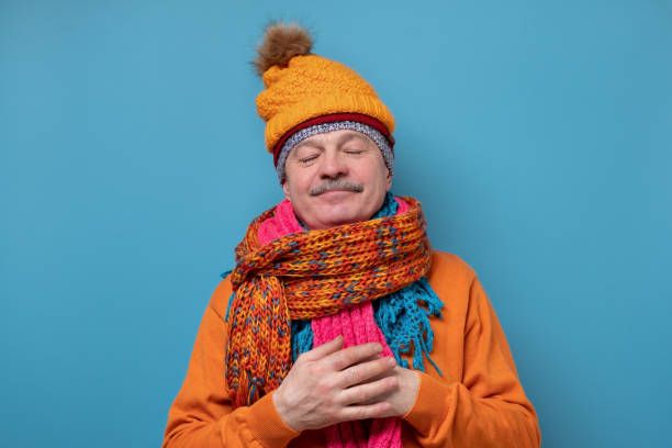 istock Funny man in several hats and scarfs standing with closed eyes 1302162548