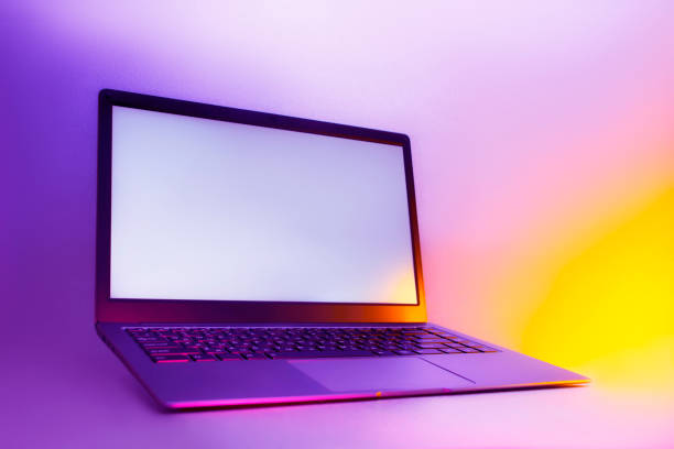 istock Slim modern laptop with white screen on the background creative light. Mockup in colorful bright neon UV blue and purple lights. 1302165098
