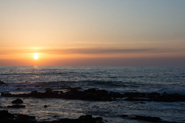 istock Sunset on the horizon and rocky shore 1302169679