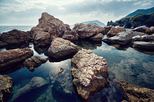 Rocky Mediterranean sea coast. Big stones. Sun reflected in water. Back light