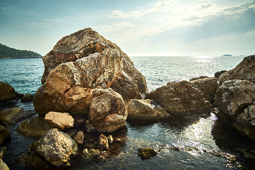 Rocky Mediterranean sea coast. Big stones. Sun reflected in water. Back light