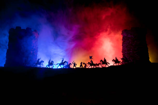 istock Medieval battle scene. Silhouettes of figures as separate objects, fight between warriors at night. Creative artwork decoration. Foggy background. 1302174372