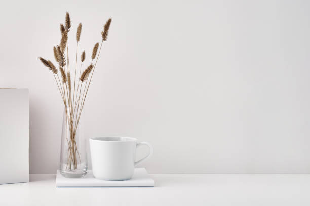 istock A transparent vase with dry branches, a book and a mug on a white background. Minimalism, eco-materials in the interior decor. Copy space, mock up. 1302174708