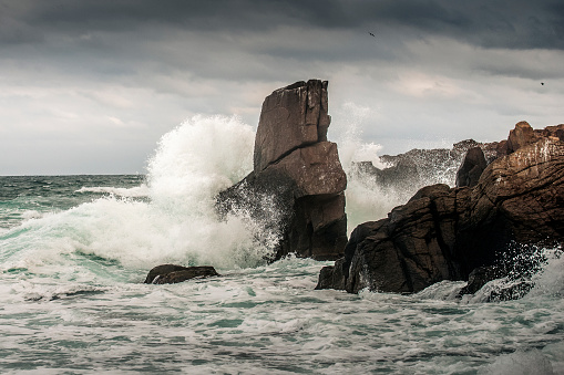 Winter sea storm on the Black sea coast. Huge waves crashes in the rocks. Dramatic dark stormy sky in the background