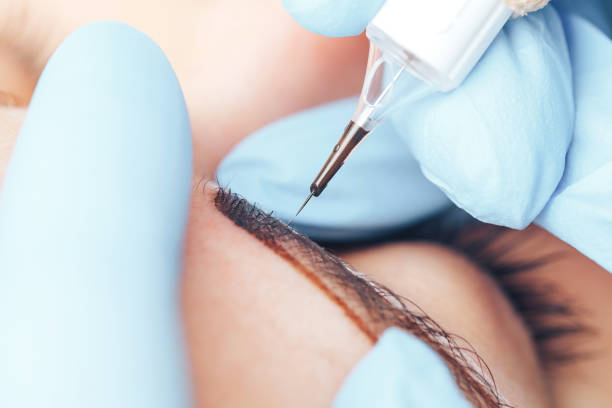 istock beautician making a permanent make-up procedure on eyebrows using a machine, macro photo of needle 1302174924