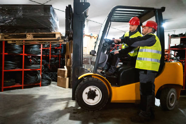 istock Warehouse driver operating forklift while his colleague giving him instructions. 1302175048