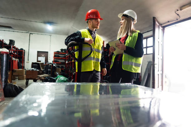 istock Young worker and warehouse manager sorting finished rubber mats for the gym in a warehouse by using a digital tablet and pallet jack 1302175053