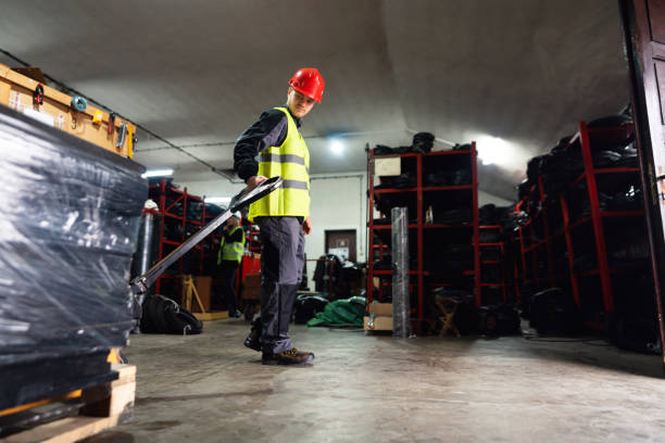 istock Worker with hand pallet jack unloading pallet goods in a warehouse 1302175055