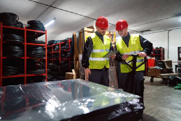 istock Two young male workers sorting finished rubber mats for the gym in a warehouse by using a digital tablet and pallet jack 1302175069
