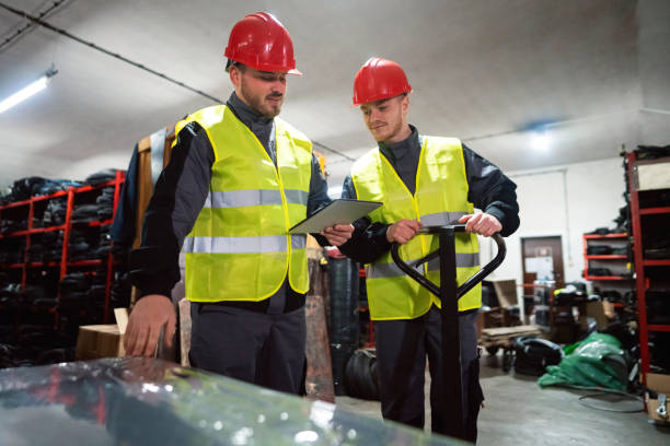 istock Two male workers sorting finished rubber mats for the gym in a warehouse by using a digital tablet and pallet jack 1302175075