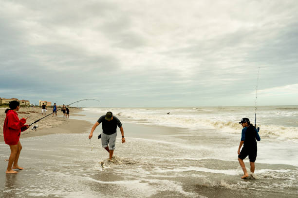 Florida, USA - January 3, 2021: A Hispanic man and his daughters fish in the Atlantic Ocean at Cocoa Beach.